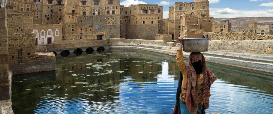 Woman carrying water jug in Yemen