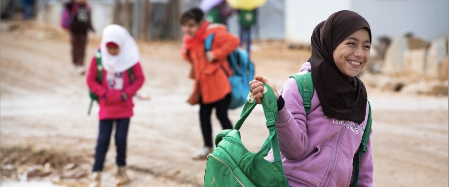 Girl in zaatari camp carrying a green backpack
